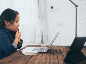 A young girl looks at her computer while remote learning