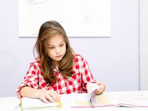 a young girl flips through a book at school