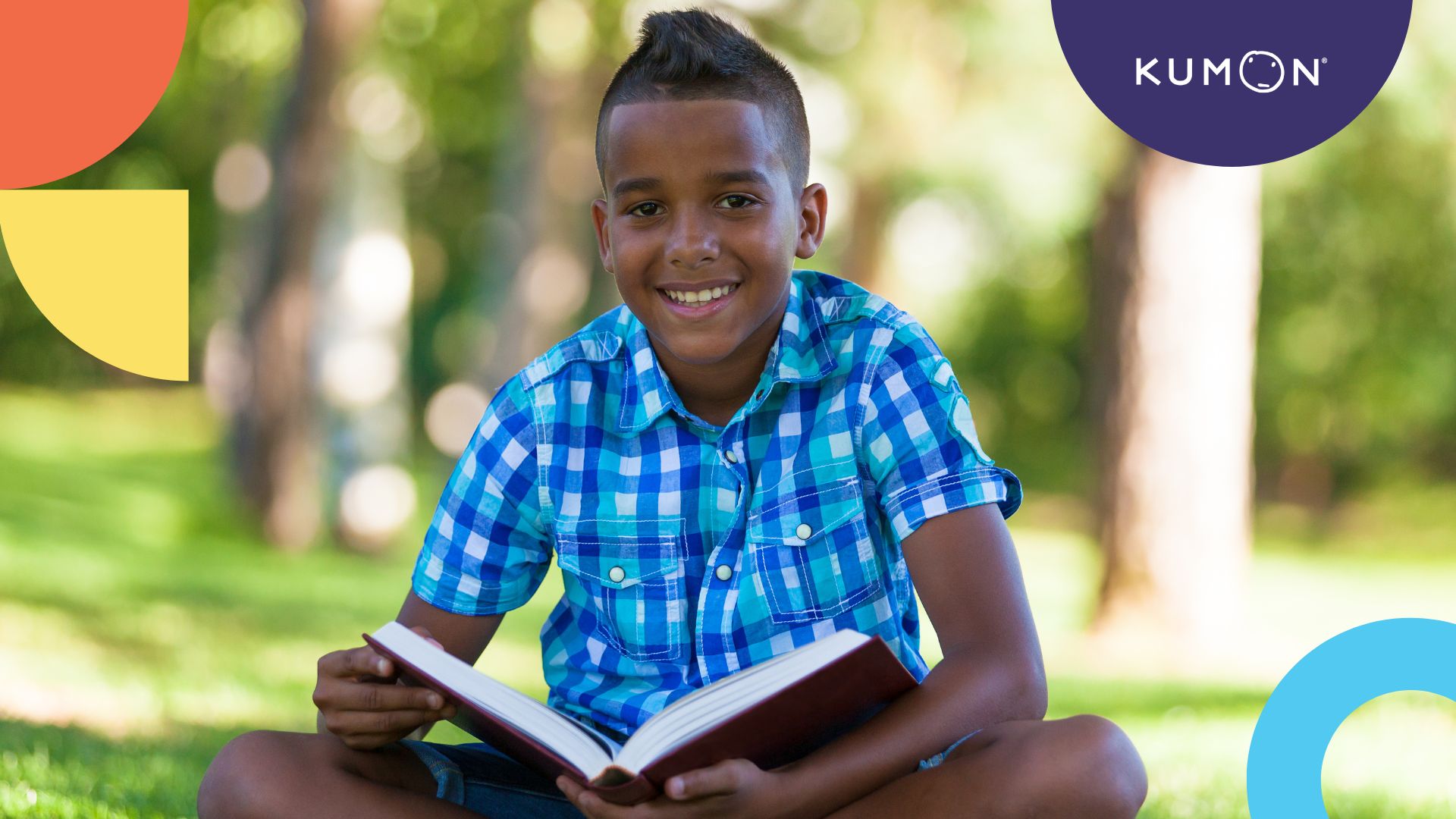 a student reading at a park pauses for a moment to smile at the camera
