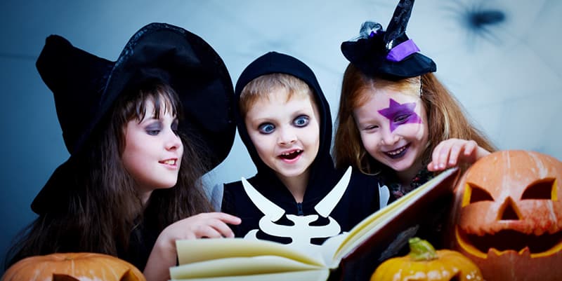 group of 3 kids in halloween costums gathered around ystery books for 8-13 year olds