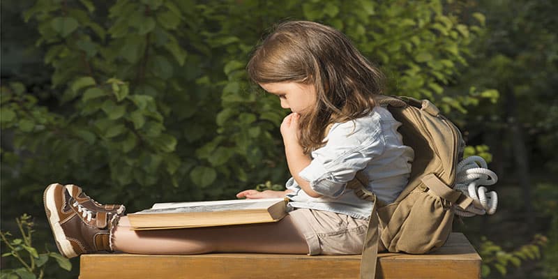 little boy reading outside