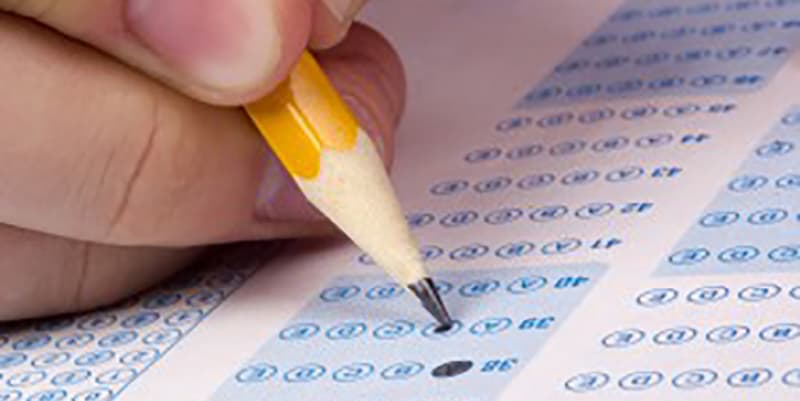 a child's hand bubbling a scantron for standardized test prep