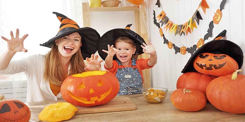two kids dressed for Halloween practicing pumpkin math at a table full of carved pumpkins