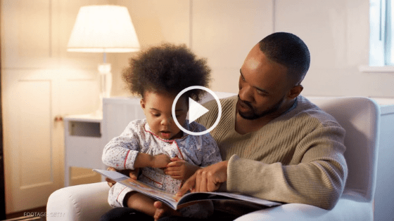 Father reads poetry to his child in a chair.