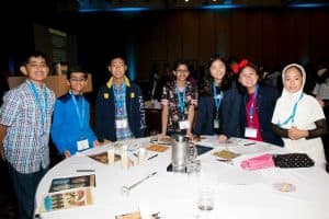 Christine stands around a table with other students at the Student Conference.