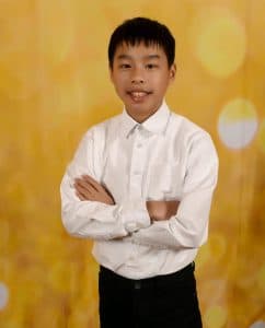 Nathan standing in a white shirt in front of a gold background