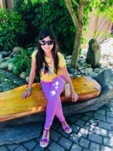 Zoha sits on a bench with sunglasses on.