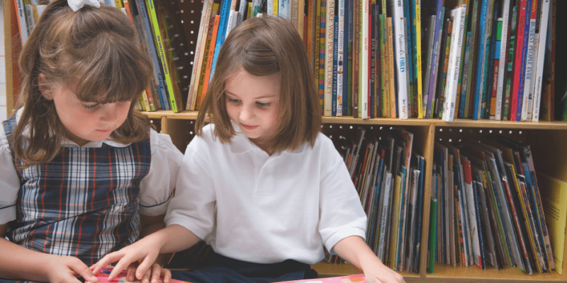 girls reading in front of a bookshelf