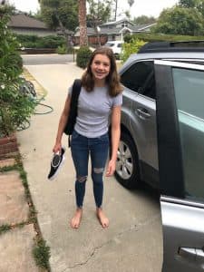 Haley stands outside a car with her school backpack