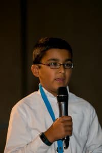 Abhinav speaks into a microphone at the student conference