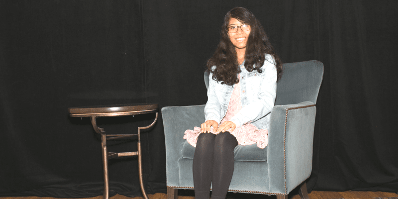 Uma poses in a blue chair at the student conference