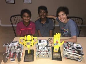 Robo Rangers team members sit at a table with trophies