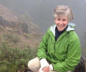 Ann poses on an mountain wearing a windbreaker