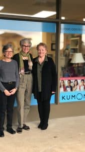 Ann poses in front of her center with her center assistants