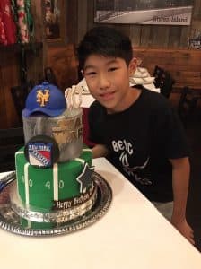Isaac poses in front of a cake