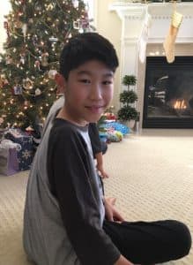 Isaac sits in front of a Christmas tree