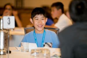 Isaac smiles while sitting at a table at the Student Conference