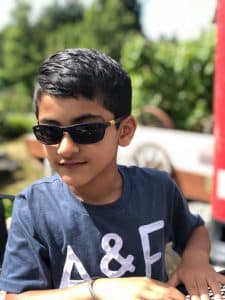 Waris poses in sunglasses and a blue tshirt