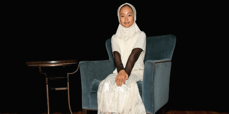 Amina sits in a chair at the student conference