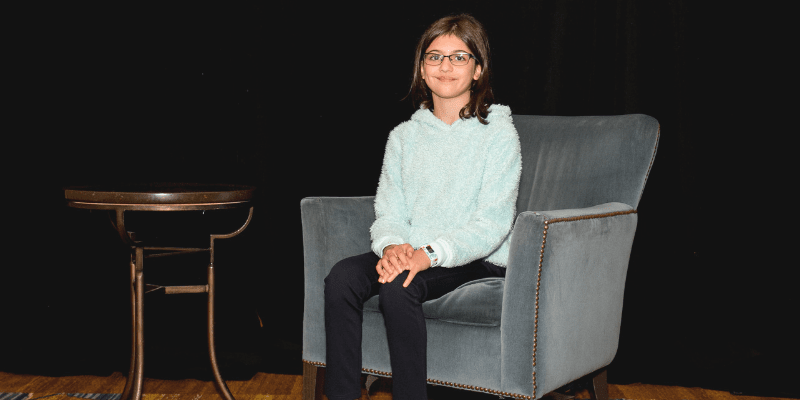 Cara poses in a chair at the Student Conference