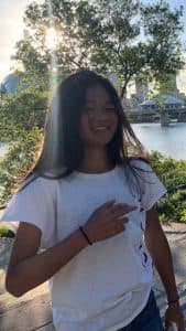 Hazel smiles in a white shirt in front of a river
