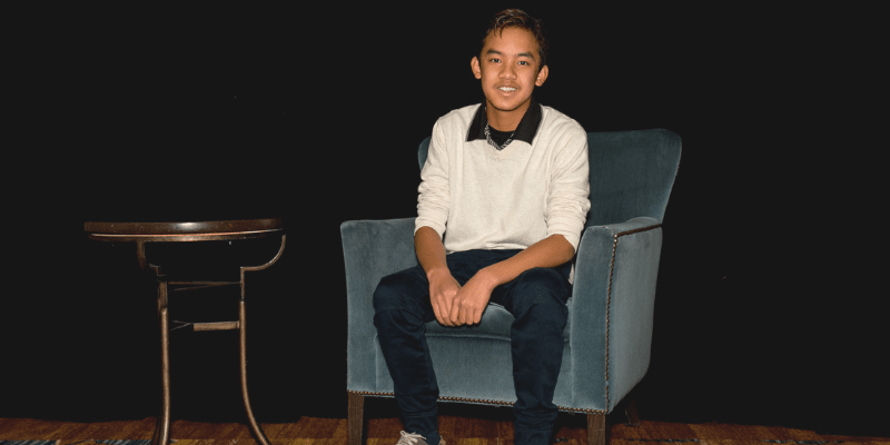 Joshua poses in a chair at the student conference