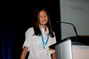 Hazel stands in front of a podium at the student conference