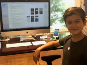 Yaseen stands proudly in front of his computer