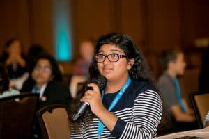 Zainab answers a question holding a microphone at the student conference