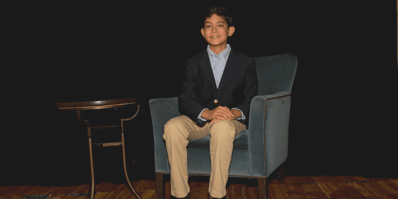 Nicholas sits in a chair at the student conference