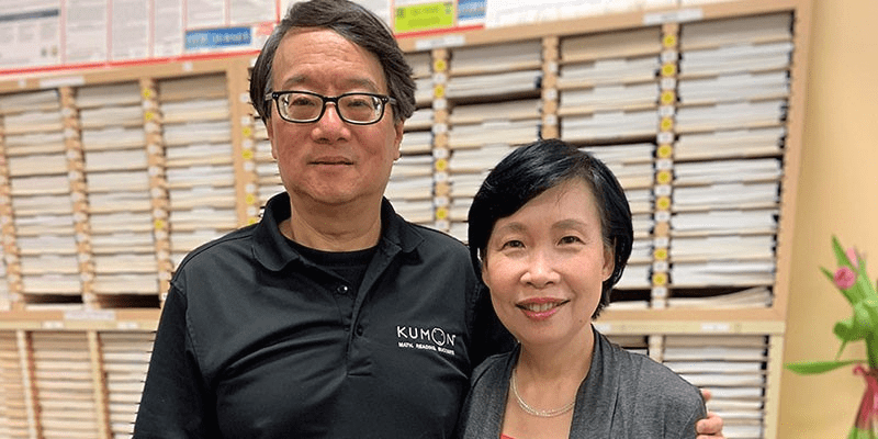 Sherman and Margaret stand in front of a worksheet shelf