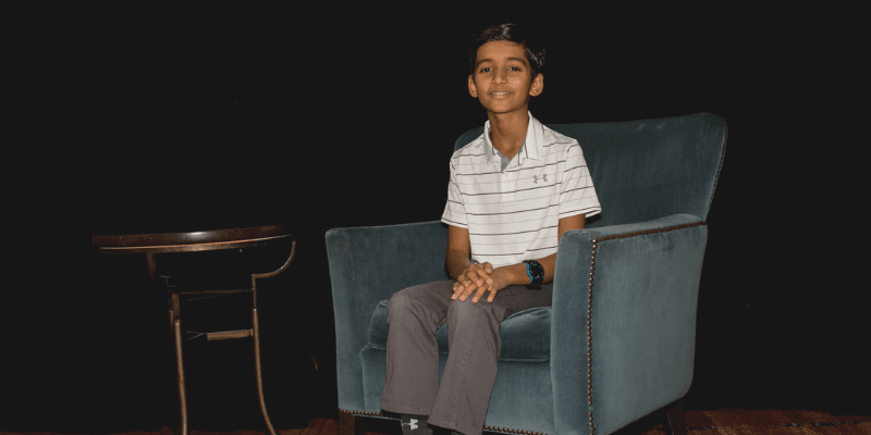 Aryan sits in a chair at the student conference
