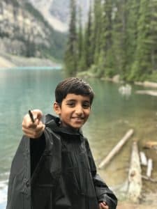 Aryan holds a stick like a wand while wearing a poncho in Banff