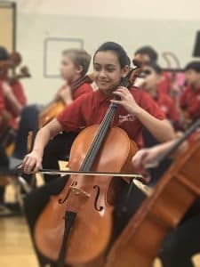 Keya plays the cello in a practice room with her classmates