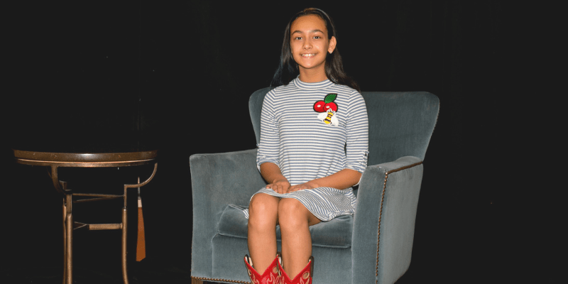 Keya sits in a chair wearing a striped dress