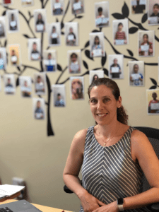 Lillian sits in her center with a tree of students' photos behind her