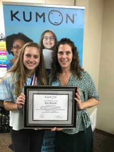 Lillian stands with her daughter holding her Kumon program completer plaque