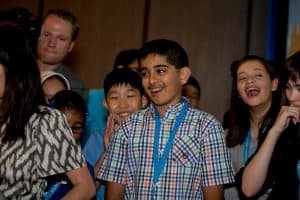 Ravi smiles in front of a group of other students at the student conferene