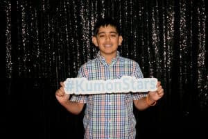 Ravi holds a #KumonStars signin front of a shiny black background