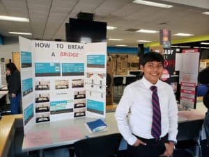 Ankit stands in front of a trifold poster at a science fair