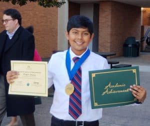 Ankit proudly holds certificates while wearing a medal