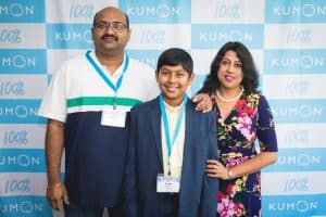 Ankit poses with his parents in front of a Kumon backdrop