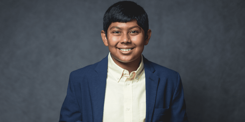 Ankit smiles in front of a gray background