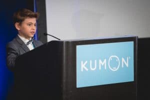 Connor stands and speaks at a podium at the student conference