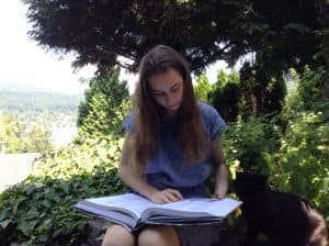 Sophia reads a large book outdoors