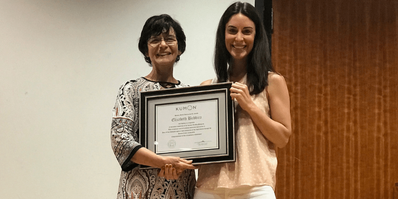 Laura stands with her daughter, displaying her program completer plaque