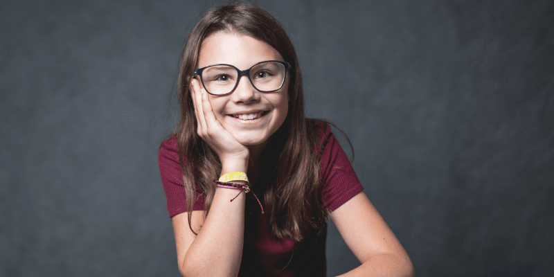 Zosia poses in a maroon top in front of a gray background