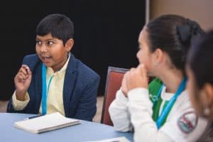 Ankit speaks to the other students at his table at the student conference