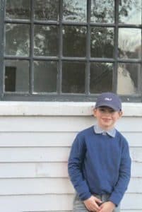 Young connor stands against a house wearing blue