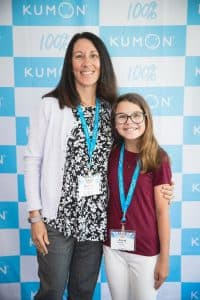 Zosia poses with her mom in front of the Kumon backdrop at the student conference